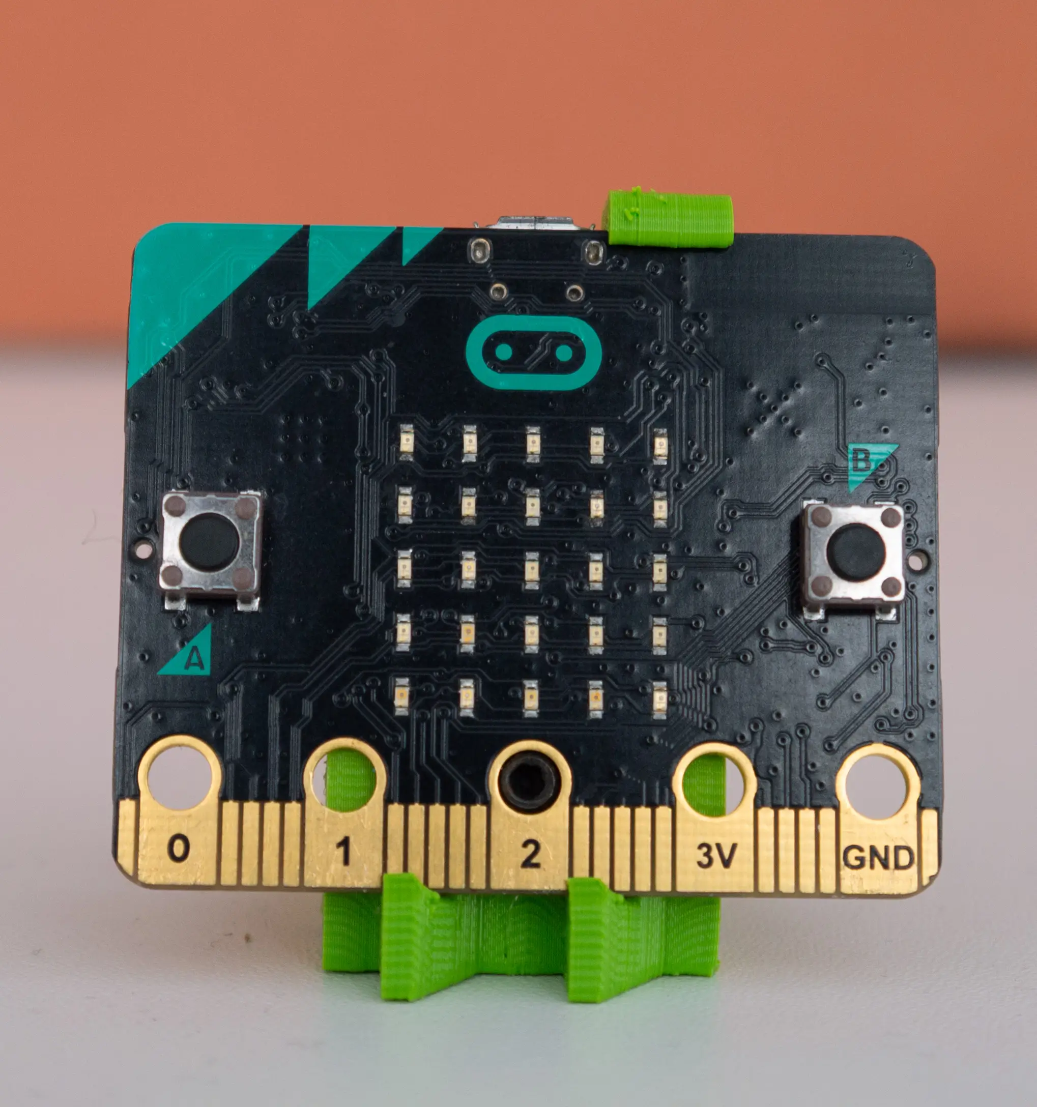 A micro:bit held upright in a green 3D-printed stand